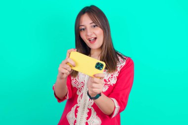 Heyecanlı genç beyaz bir kadının portresi cep telefonuyla oyun oynuyor..