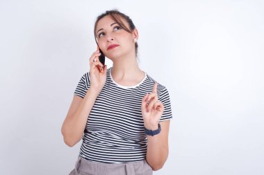 Tişört giyen güzel beyaz kadın cep telefonuyla konuşuyor. Boş vakitlerini içeride arkadaşlarıyla konuşarak geçiriyor..