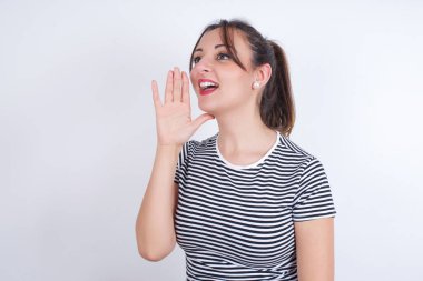 Genç, güzel, beyaz bir kadın boş alana bakıyor. Yüzünün yanında el ele tutuşuyor ve bağırıyor ya da birini arıyor..