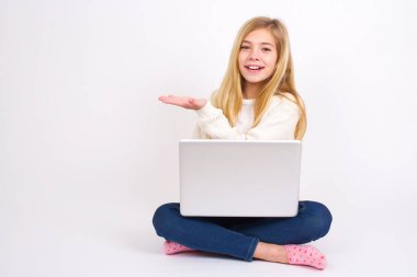 Beyaz arka planda dizüstü bilgisayarı olan beyaz bir genç kız der ki: Vay be, ne kadar heyecan verici, hayret verici bir ifade, boş alanda avuç içi ile bir şeyler gösteriyor. Reklam kavramı.