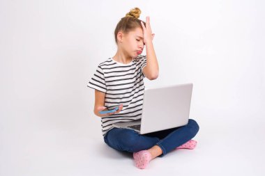 Morali bozuk. Beyaz arka planda dizüstü bilgisayarı olan beyaz tenli güzel beyaz bir kız, cep telefonunun taşıdığı önemli bir şeyi unutuyor. Üzüntüyü ve pişmanlığı ifade ediyor.