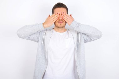 Beyaz arka plan üzerine günlük kıyafetler giyen genç beyaz bir adam iki eliyle gözlerini kapatıyor, hiçbir şey görmek ya da utanmak istemiyor. İnsani duygular tepki verir.