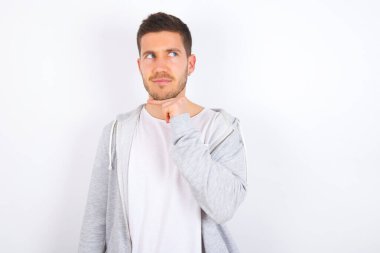 Beyaz arka plan üzerine günlük kıyafetler giyen, hoş bir yüz ifadesi olan, yan bakan, elini çenesinin altında tutan, hoş bir şeyler düşünen hayalperest beyaz bir adam..
