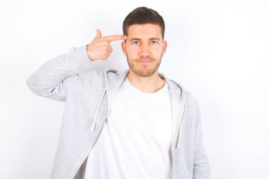 Mutsuz, beyaz arka plan kıvrımlı, günlük kıyafetler giyen beyaz bir adam dudaklarını kıvırıyor ve intihar jesti yapıyor, eliyle şakağına ateş ediyor, kendini öldürmeye çalışıyor..