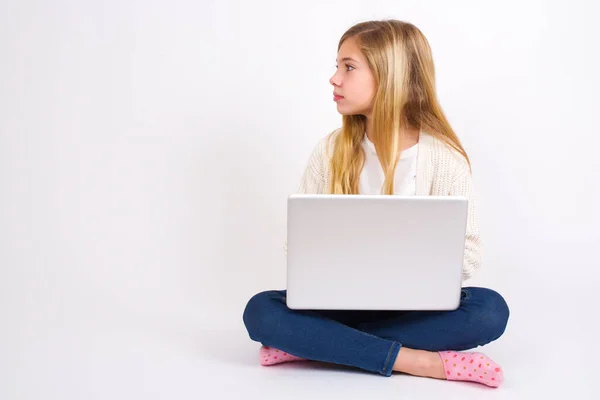 側ビューの若いです幸せな笑顔Caucasianティーン女の子座っていますノートパソコンで蓮の位置に白の背景 — ストック写真