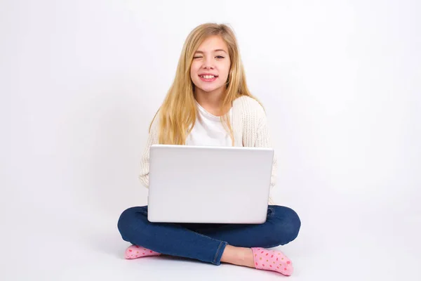 白人の10代の女の子が喜びの表情で目を点滅白の背景にハスの位置にノートパソコンで座っています 顔の表情や人の感情の概念 — ストック写真
