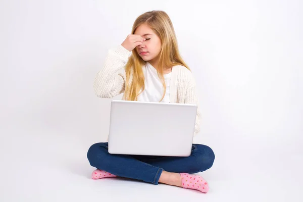 非常心烦意乱 白人少女坐在笔记本电脑前 白色背景 双目紧闭 鼻梁紧闭 与人关系紧张 或工作有问题 — 图库照片