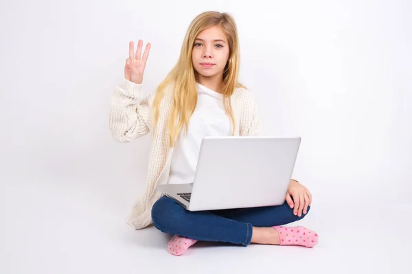 白人女の子座っていますノートパソコンで蓮の位置の上に白い背景を示すと指番号3で指摘しながら 自信と幸せ — ストック写真