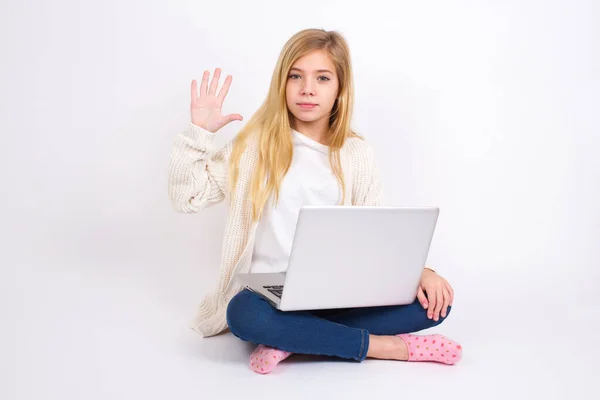 白人女の子座っていますノートパソコンで蓮の位置の上に白の背景表示と指差しますと指番号5ながら笑顔自信と幸せ — ストック写真