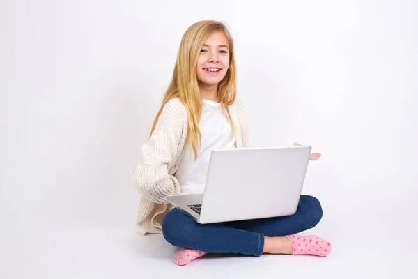 ポートレートのCaucasianティーン女の子座っていますノートパソコンで蓮の位置の上にホワイトバックグランドとともにアームアウトで歓迎ジェスチャー — ストック写真