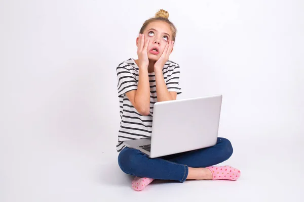 漂亮的高加索少女 背著白色背景的荷花式笔记本电脑 双手放在脸颊上 有着令人厌烦的不愉快的表情 紧张绝望的模式 — 图库照片