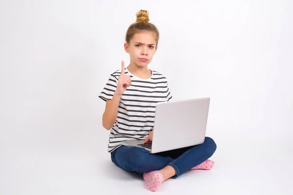美しいですCaucasianティーン女の子座っていますノートパソコンでハスの位置に白の背景不満と前を指して — ストック写真