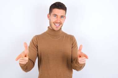 Beyaz arka plan üzerine balıkçı yaka giyen genç beyaz bir adam parmaklarını kameraya doğrultuyor ve birini seçiyor. Seni tavsiye ederim. En iyi seçim