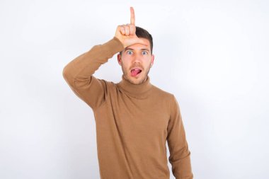Kafkasyalı genç adam, alnına parmak atarak ezik jestler yapar. 