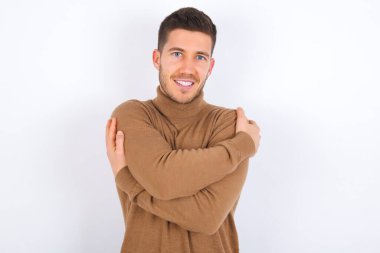 Cazibeli adam kendi vücudunu kucaklıyor, rahat pozlar veriyor. Şefkat ve kendine saygı kavramı