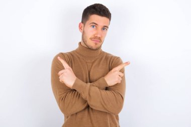 Genç beyaz adam kollarını kavuşturur ve farklı tarafları işaret eder. İki nesne ya da varyant arasında tereddüt eder. Karar vermede yardıma ihtiyacı var