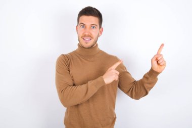 Genç beyaz adam fotokopi alanını işaret ediyor. Reklam için doğru yönü gösteriyor.