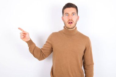Beyaz arka plan üzerine balıkçı yaka giyen genç beyaz adamın şok yüzünden çenesinin düşmesi, boş alan üzerindeki inanılmaz reklam noktalarını gösteriyor ki büyük bir alışveriş satışı var. Reklam.