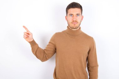 Beyaz arka plan sırıtışları üzerine balıkçı yaka giyen, ciddi, genç beyaz bir adam fotokopi alanındaki yüz ifadeleri hoş olmayan bir şey gösteriyor. Şu reklama bak. Büyük fiyat konsepti
