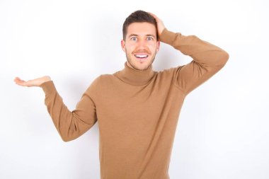 Beyaz arka plan üzerine balıkçı yaka giyen beyaz yaka giyen genç bir adamın el ele tutuşup teklif sunmasına şaşırdım.