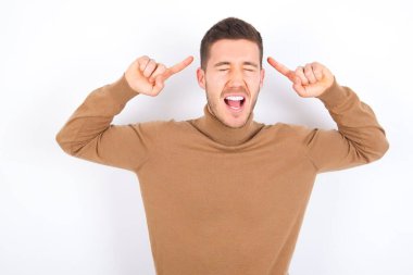 Beyaz arka plan üzerine balıkçı yaka giyen çılgın beyaz bir adamın fotoğrafı. Çığlık atıyor ve parmakları saçları kapalı gözleri işaret ediyor.