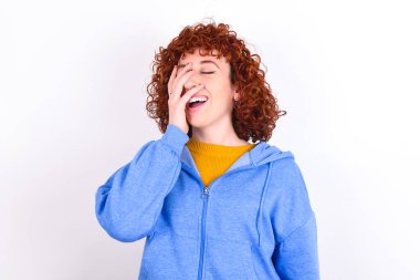 Karizmatik, kaygısız, neşeli, beyaz arka planda mavi ceketli genç bir kız duygularını gizlemeden kahkahalar atmayı seviyor..