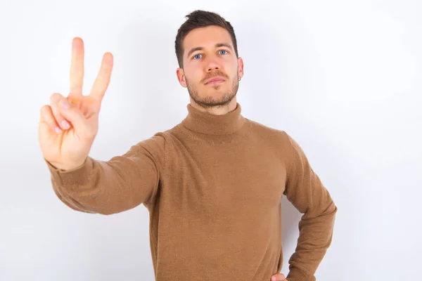 Young Caucasian Man Wearing Turtleneck Showing Victory Gesture White Background — Stock Photo, Image