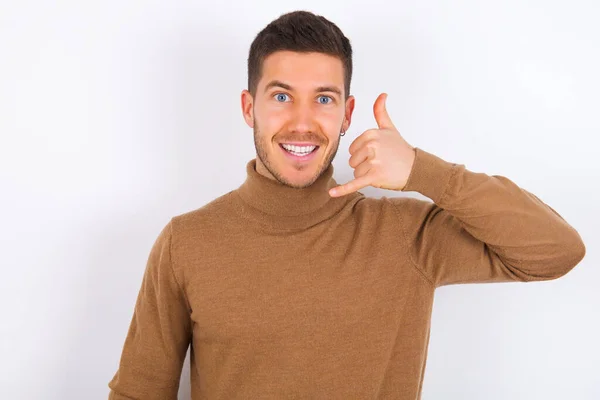 Young Caucasian Man Wearing Turtleneck White Background Makes Phone Gesture — Stock Photo, Image