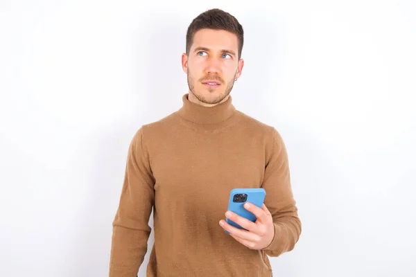 Young Caucasian Man Wearing Turtleneck White Background Holds Mobile Phone — Stock Photo, Image