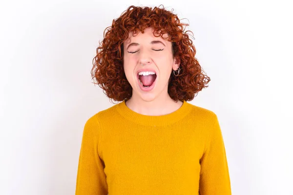 Stressful Young Redhead Girl Wearing Yellow Sweater White Background Screams — Stock Photo, Image