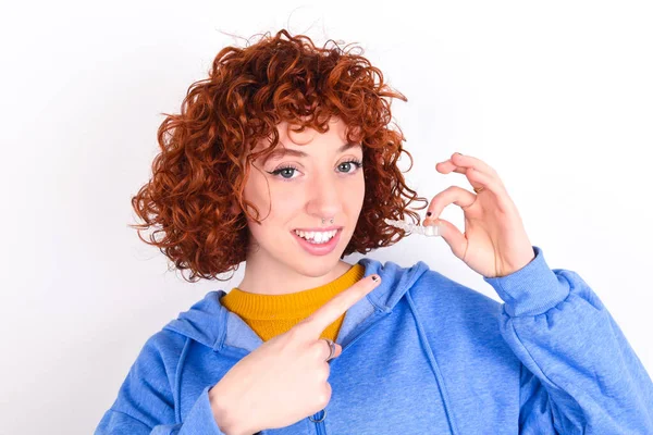 Joven Pelirroja Vistiendo Chaqueta Azul Sobre Fondo Blanco Sosteniendo Alineador —  Fotos de Stock