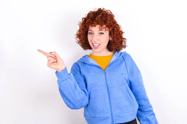 Young Redhead Girl Wearing Blue Jacket White Background Points Aside — Stock Photo, Image