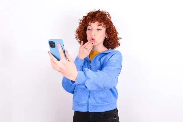 Joven Pelirroja Vistiendo Chaqueta Azul Sobre Fondo Blanco Sopla Aire —  Fotos de Stock