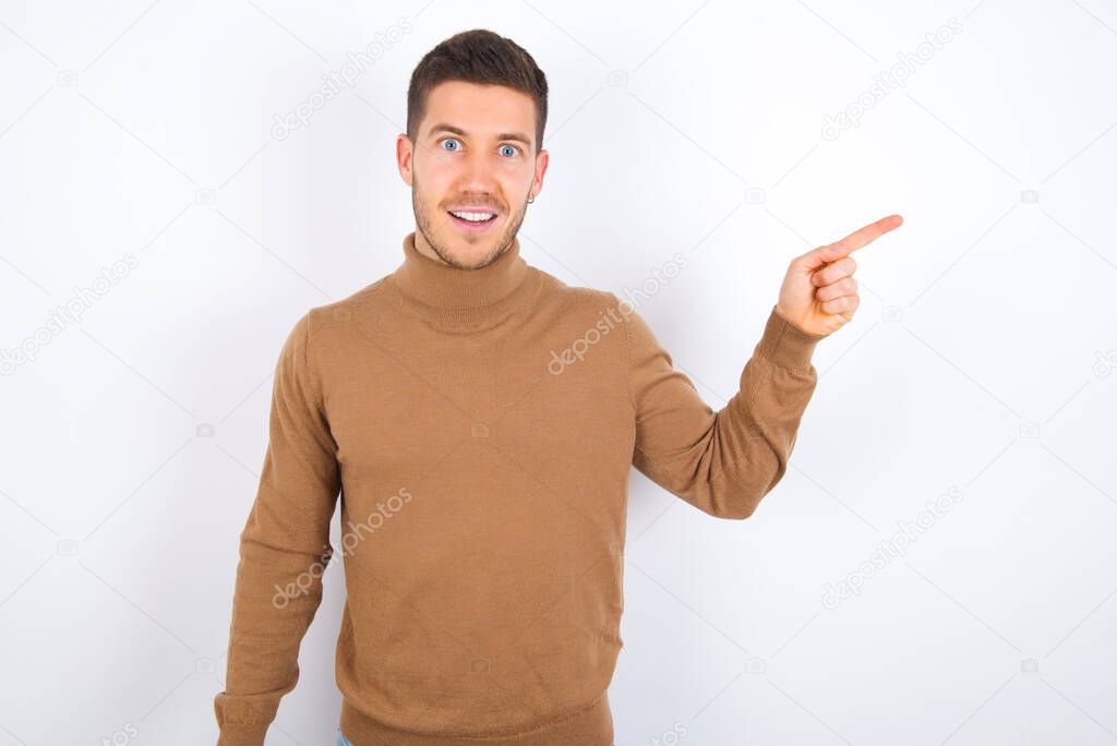 young caucasian man wearing turtleneck over white background points aside on copy blank space. People promotion and advertising concept