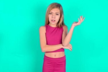 Studio shot of frustrated  little caucasian kid girl    gesturing with raised palm, frowning, being displeased and confused with dumb question.