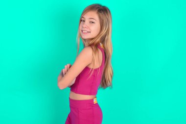 Kollarını kavuşturmuş neşeli, beyaz bir kızın resmi. Kameraya bakıp gülümsüyor. Güven kavramı.