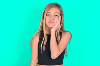 Üzgün, yalnız, beyaz, küçük kız yanağına dokunuyor, dudaklarını ısırıyor ve hoşnutsuzca bakıyor. Kötü duygular