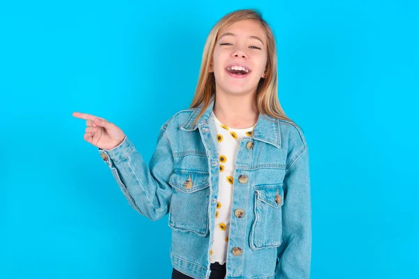 Loira Caucasiana Menina Vestindo Jaqueta Jeans Alegremente Aponta Para Longe — Fotografia de Stock