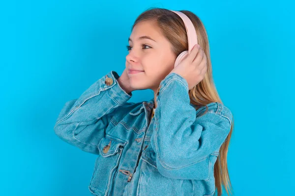 Niña Rubia Con Chaqueta Mezclilla Sobre Fondo Azul Lleva Auriculares —  Fotos de Stock