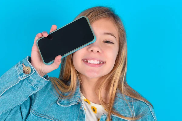 Μικρό Καυκάσιο Κοριτσάκι Κρατώντας Σύγχρονο Smartphone Που Καλύπτει Ένα Μάτι — Φωτογραφία Αρχείου
