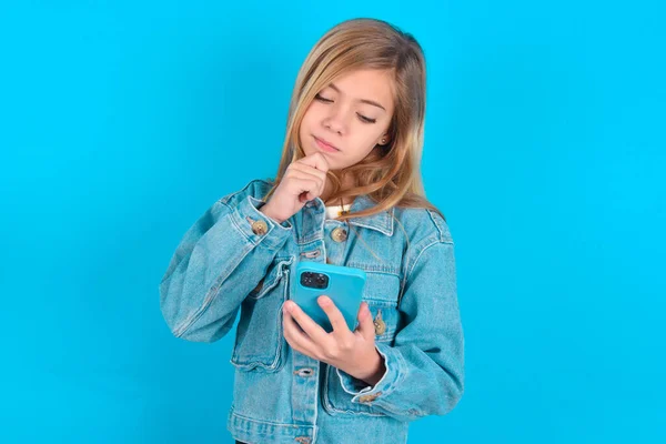 思慮深い幸せな小さな白人少女は電話 コピースペースを見ている — ストック写真