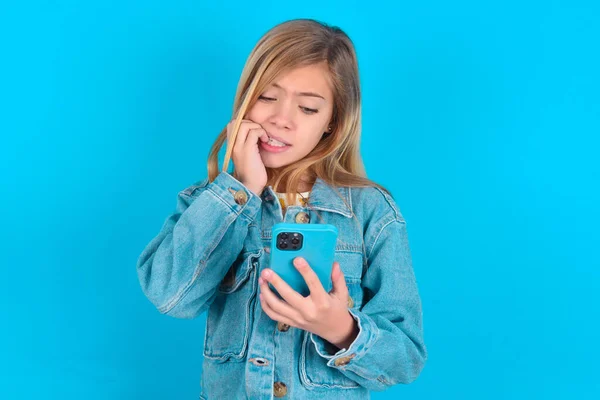 彼女のスマートフォンでいくつかの怖いニュースを読んだ後 爪を噛んでチャット可愛い小さな白人少女の肖像画 — ストック写真