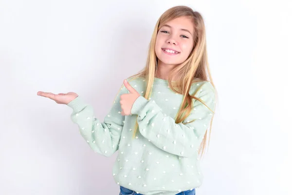girl Showing palm hand and doing ok gesture with thumbs up, smiling happy and cheerful.