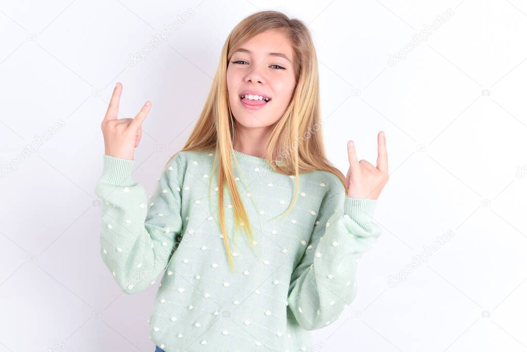 little caucasian kid girl  making rock hand gesture and showing tongue