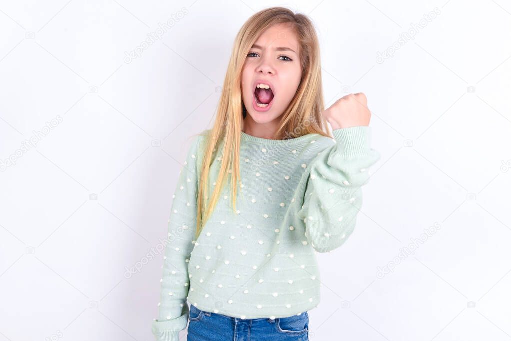 little caucasian kid girl   angry and mad raising fist frustrated and furious while shouting with anger. Rage and aggressive concept.