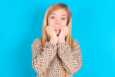 Korkak beyaz kız ellerini ağzının kenarında tutuyor, korkmuş ve korkmuş hissediyor, fobisi, şoku ve korkmuş bir konsepti var..