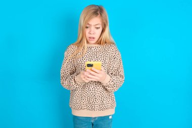 Akıllı telefon kullanarak sosyal medya haberleri ya da önemli e-postalar okuyan beyaz bir kız çocuğu.