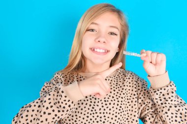 Kafkasyalı bir kız, görünmez bir rakip tutuyor ve onu işaret ediyor. Diş sağlığı ve güven kavramı.