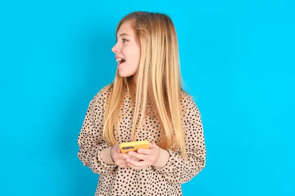 Niña Caucásica Sosteniendo Teléfono Inteligente Mirando Hacia Los Lados Blanco — Foto de Stock