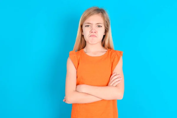 Ponura Niezadowolona Dziewczynka Nosi Pomarańczowy Shirt Niebieskim Tle Wygląda Nieszczęśliwym — Zdjęcie stockowe